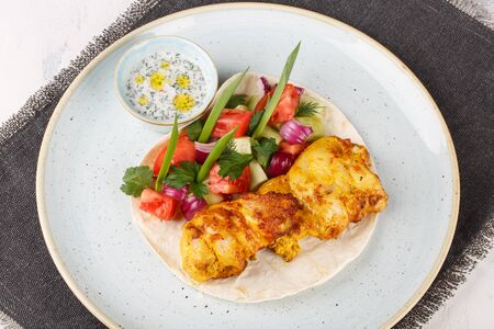 Chicken skewers cooked in a josper oven. Served on a plate with pita bread, vegetables and sauce.の写真素材