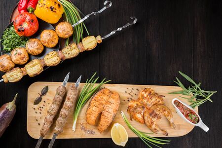 Assorted grilled meat delicacies and vegetables. Salmon steak, kebab and chicken on a wooden board. Copyspace.の写真素材