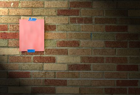 A blank piece of hot pink paper taped to a brick wall with blue tape.の写真素材