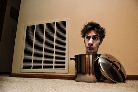 A mad man with his head peaking out of a pot laying on the floor.の写真素材