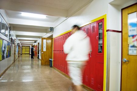 An empty highschool hallway with a person walking down it with red lockers on the right side..の写真素材