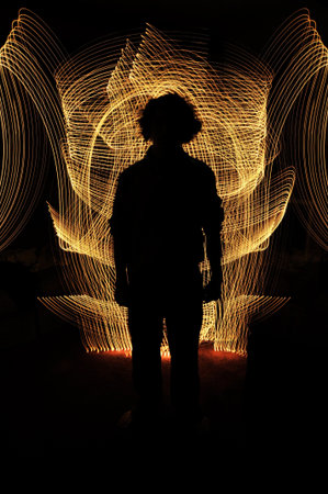 Silhouette of anonymous man standing in front of golden glowing lines. Everything else in the...
