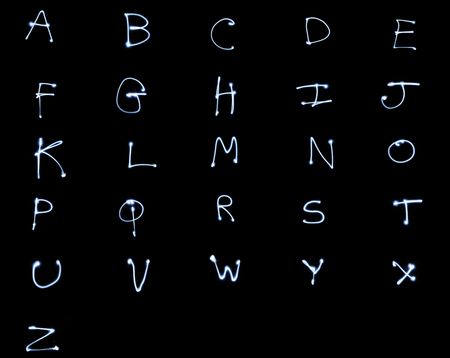 Glowing alphabet letters on black background. Long exposure light painting style. All capital lettersの写真素材