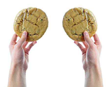 Two hands holding two cookies that are in shrink wrap isolated on a white backgroundの写真素材
