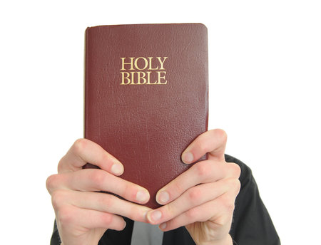 Person holds up the Holy Bible in front of their face