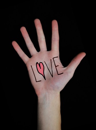 The word love written on a teenager's white Caucasian hand isolated on black background.の写真素材