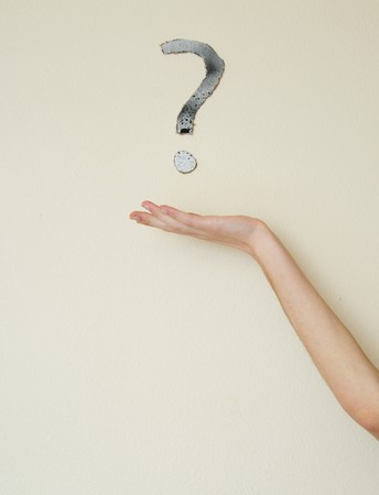 Young white Caucasian male wondering with a question mark above his head on the wall behind him. Focus point is on the person.の写真素材