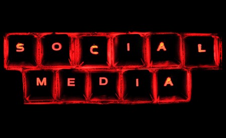The word social media on a glowing computer keyboard isolated on black.の写真素材