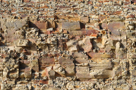 A bunch of chunky sandstone rocks on a cliff create a rough texture with shadows included.