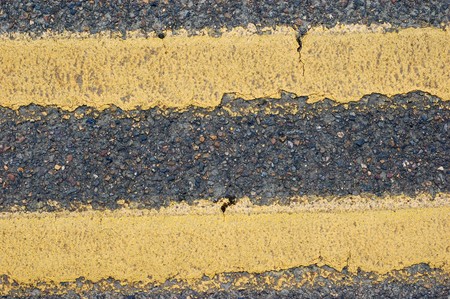 Cracks in a double yellow lined road. Makes a good textureの写真素材