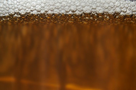 A closeup of dark beer in a cup with bubble suds at the topの写真素材
