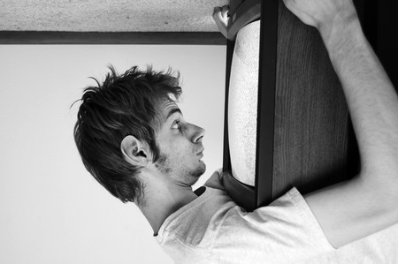 An old CRT TV plugged into the wall with static on the screen with a man watching it closely.の写真素材