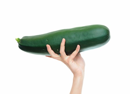 Large zucchini vegetable plant held by a white hand isolated on white backgroundの写真素材