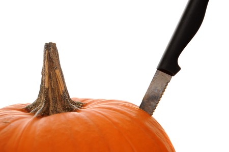 Orange pumpkin  isolated on a white background with a knife stabbed in the side to demonstrate a pumpkin carving theme.の写真素材