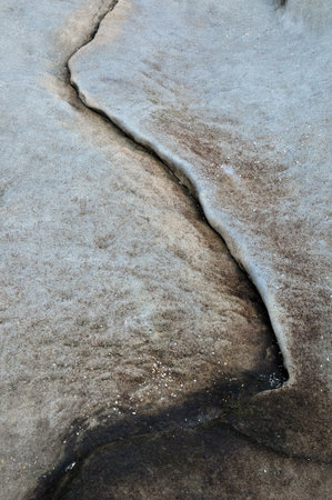 Abstract minimalistic texture of a single line crack on a large rock surface