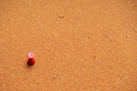 a single red tack on a corkcoard background with shallow depth of field.の写真素材