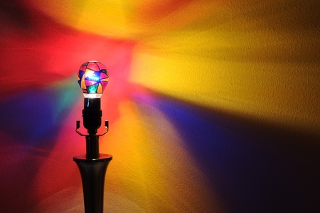 A colorful lightbulb with painted rainbow colors projecting onto the wall behind it with copyspace with room for your textの写真素材