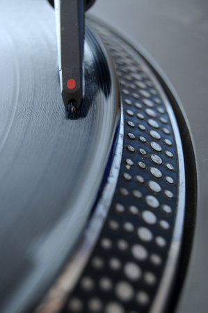 DJ record player with a macro closeup of the stylus on a 12 inch vinyl LP playing hiphop techno rave...