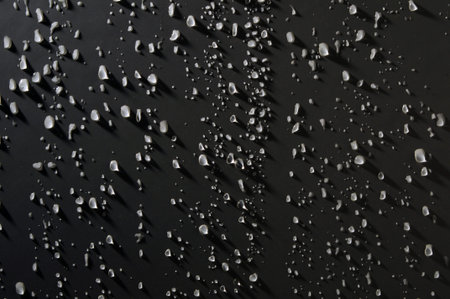 Water drops on a dark surface. The water droplets are very bright and contrast well with the dark...