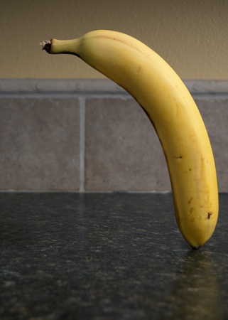 Banana floating over a plate chopped up over a kitchen counter top.の写真素材