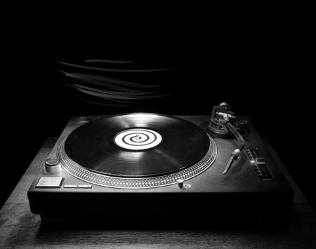 Single DJ turntable record player sitting on a small wooden table in the darkness