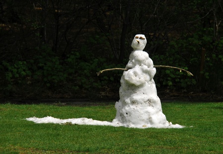 A sad snowman melting in the grass when the sun comes outの写真素材