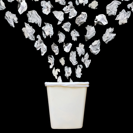 Bunch of cumbled paper being throwing into a trash bin or waste bin isolated on black background.の写真素材