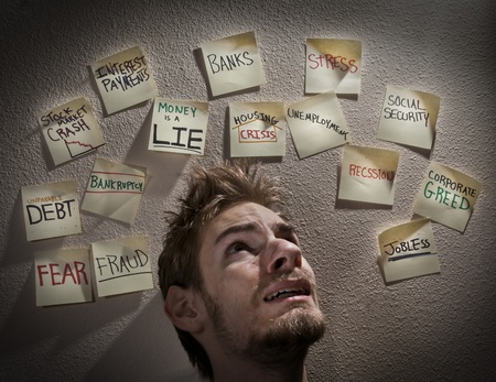 Young white Caucasian male is overwhelmed with stress and worry about the bad economy crises during this economic recession or depression.の写真素材