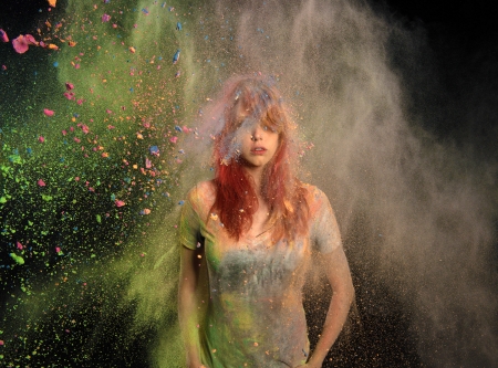 Redhead girl with colored powder exploding around her and into the background.の写真素材
