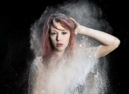 Redhead girl with colored powder exploding around her and into the background.の写真素材