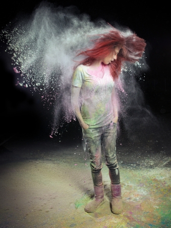 Redhead girl with colored powder trailing behind her hair that she is flinging up. の写真素材