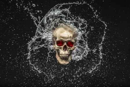 Skull with water splashing around it over a black backgroundの写真素材