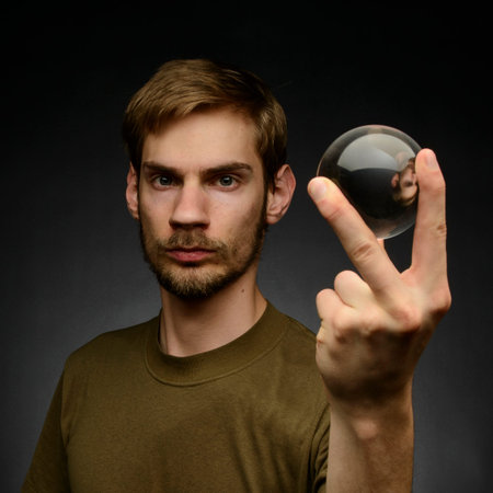 Young man holding a clear transparent crystal glass ball in their hand