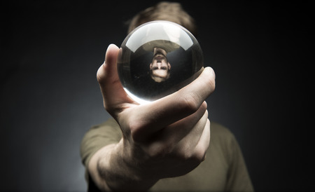 Young man holding a clear transparent crystal glass ball in their handの写真素材