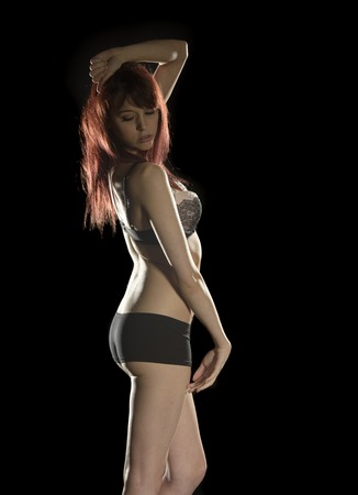 Side View Portrait of Sensual Young Woman Posing in Gray Underwear. Captured in Studio on Black Background.の写真素材