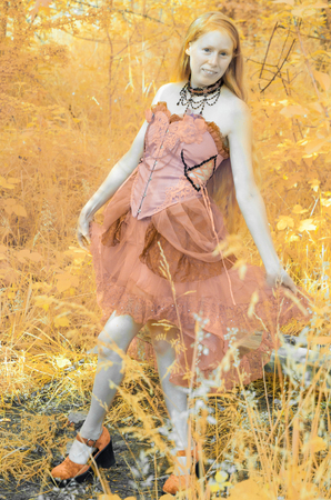 Colorized Full Length Portrait of Young Woman Wearing Pink Gown Walking on Forest Path and Looking at Cameraの写真素材