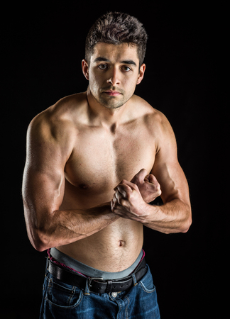 Personal fitness trainer flexing his muscles isolated on black backgroundの写真素材