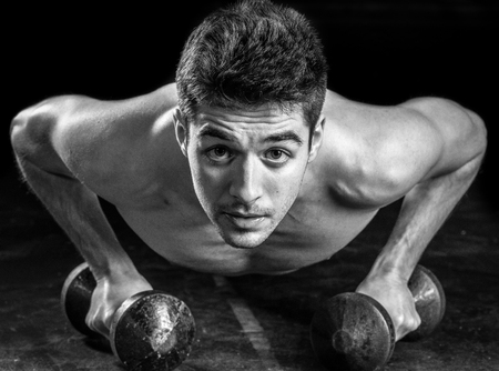 Young Athlete Doing Pushups With Dumbbells As Part Of Bodybuilding Trainingの写真素材
