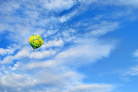 Yellow green hot air balloon is rising up to the blue sky with clouds. Hot air balloon on picturesque sky backgroundの写真素材
