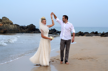 Happy white newlyweds dancing on the seasideの写真素材