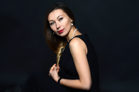 White woman with red lips in pearls jewelry in the black dress on the dark backgroundの写真素材