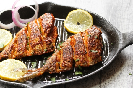 Marinated fried fish / Spicy  fish fry with spices n lemon juice on iron skillet griddle, selective focusの写真素材