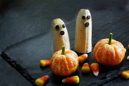 Halloween food Banana ghosts and Clementine Pumpkins on dark spooky backgroundの写真素材
