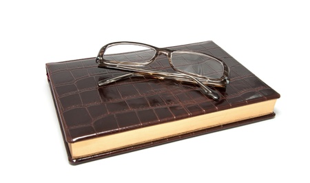 Leather diary and glasses on a white backgroundの写真素材
