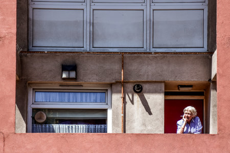 An elderly woman smokes a cigarette on the balcony in socialistic houseのeditorial素材