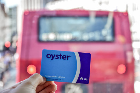 London, England - July 07 2017: Hand holding the blue Oyster card behind the red bus doubledeckerのeditorial素材
