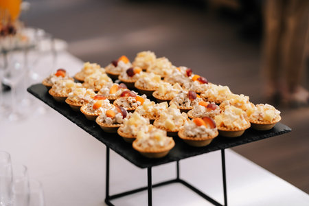 Tartlets. Snacks on the wedding table with meat in waffle baskets with cheese, meat and grapes light...