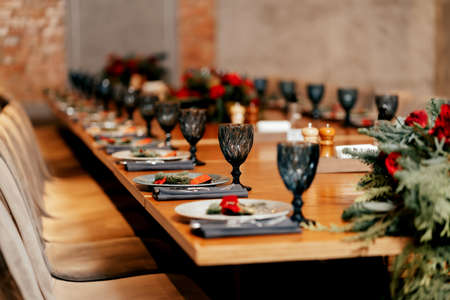 in a loft-style restaurant there is a long table served with glasses, plates with warm lighting and paintingsの写真素材