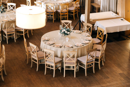 Beige wooden chairs stand at round dinner tables the restaurant