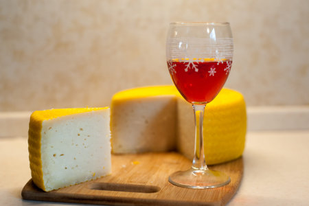 Home-made goat cheese and a glass of red wine on a wooden plank